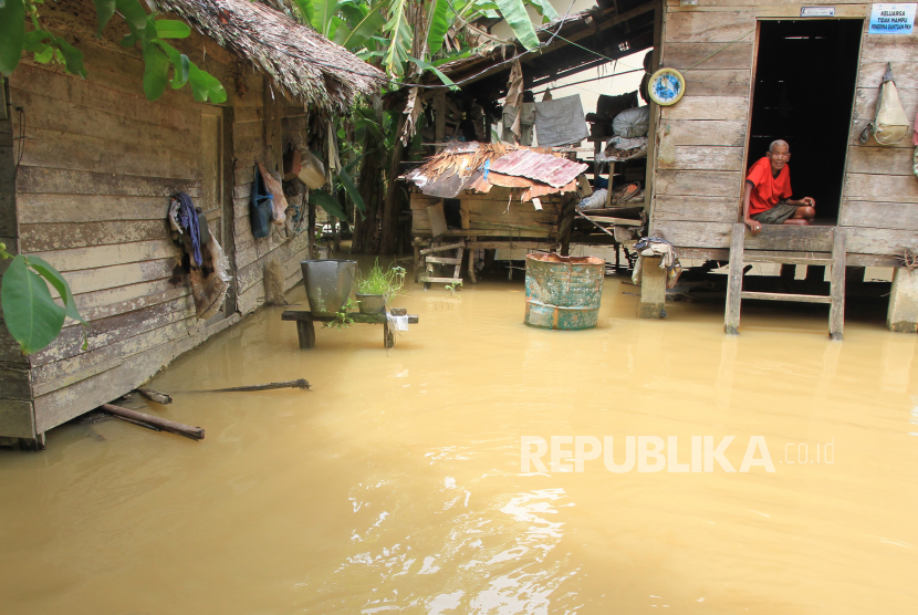 Seorang warga berada di dalam rumahnya yang digenangi banjir. Ilustrasi