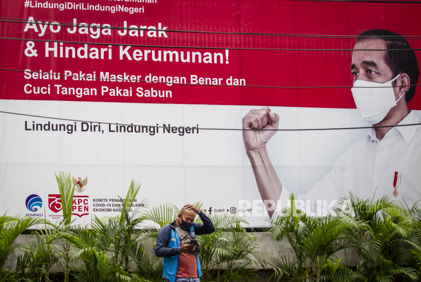 Warga beraktivitas di depan baliho informasi tentang pandemi Covid-19 di Jakarta. (ilustrasi)