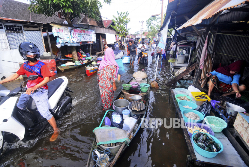 Orang-orang melewati air banjir di Banjarmasin, Kalimantan Selatan, Minggu, 17 Januari 2021. ribuan orang telah dievakuasi dan sejumlah lainnya tewas dalam beberapa hari terakhir akibat banjir di pulau Kalimantan, Indonesia.