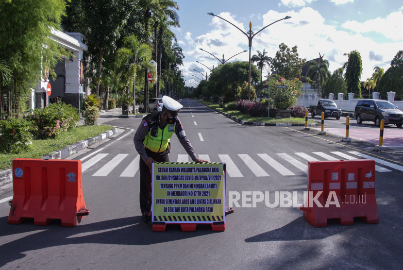 Anggota Polisi mendorong pembatas jalan saat penutupan ruas jalan pusat kota di Jalan DI Panjaitan, Palangkaraya, Kalimantan Tengah, Jumat (9/7/2021). Penutupan sejumlah ruas titik jalan protokol di pusat kota tersebut untuk mengurangi pergerakan mobilitas dan penegakan aturan Pemberlakuan Pembatasan Kegiatan Masyarakat (PPKM) Mikro guna menekan angka penularan COVID-19 yang semakin meningkat. 