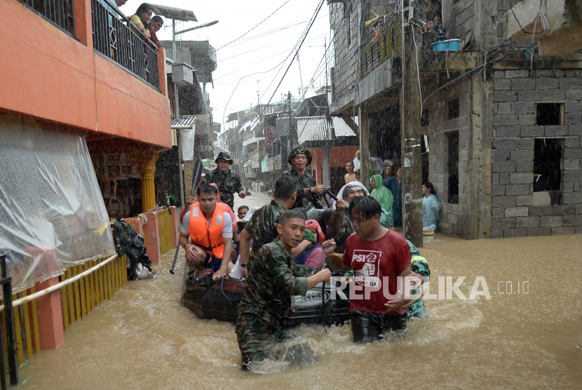Anggota TNI  mengevakuasi sejumlah warga dari rumahnya yang terendam banjir di Manado, Sulawesi Utara, Jumat (27/1/2023). Hujan deras sejak dini hari mengakibatkan banjir dan longsor di sejumlah lokasi di kota Manado. 