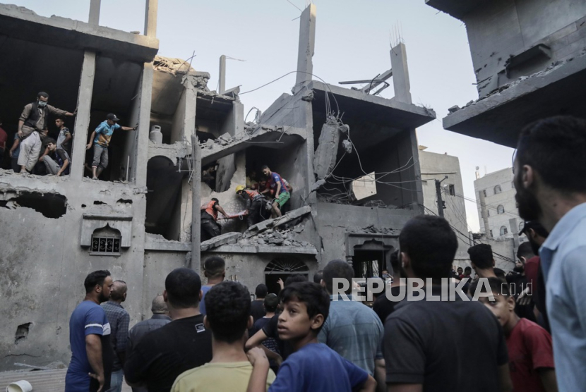 Warga Palestina mencari mayat dan korban di reruntuhan bangunan tempat tinggal yang rata akibat serangan udara Israel, di kamp pengungsi Khan Younis di Jalur Gaza selatan,  Kamis (19/10/2023). 