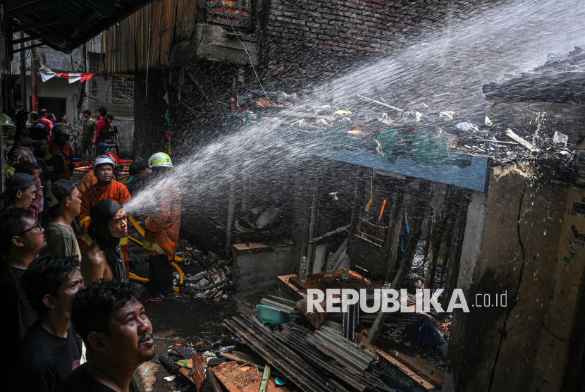 Petugas Penanggulangan Kebakaran dan Penyelamatan (Gulkarmat) melakukan pendinginan di lokasi kebakaran permukiman padat penduduk di Jalan Jembatan Besi, Tambora, Jakarta, Rabu (13/8/2025). Sudin Gulkarmat Jakarta Barat mengerahkan 18 unit mobil pemadam dan 90 personel untuk menangani kebakaran yang melanda tiga rumah dan satu tempat usaha konveksi di kawasan pemukiman padat penduduk tersebut. 