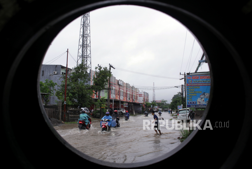 Sejumlah pengendara menerobos banjir di Jalan Paccerakkang, Makassar, Sulawesi Selatan, Jumat (18/12/2020). Banjir yang menggenangi ruas jalan disebabkan tingginya intensitas curah hujan beberapa hari terakhir dan buruknya drainase di daerah itu. 