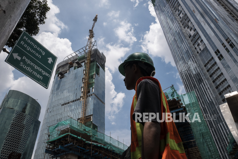 Pekerja melintas dengan latar belakang pembangunan gedung bertingkat di kawasan Kuningan, Jakarta. Bank Indonesia mulai mengambil langkah pengetatan likuiditas pada awal tahun ini. Adapun langkah pengetatan likuiditas dilakukan secara bertahap dengan menaikkan giro wajib minimum (GWM) rupiah ke Bank Umum Konvensional (BUK) dan syariah.