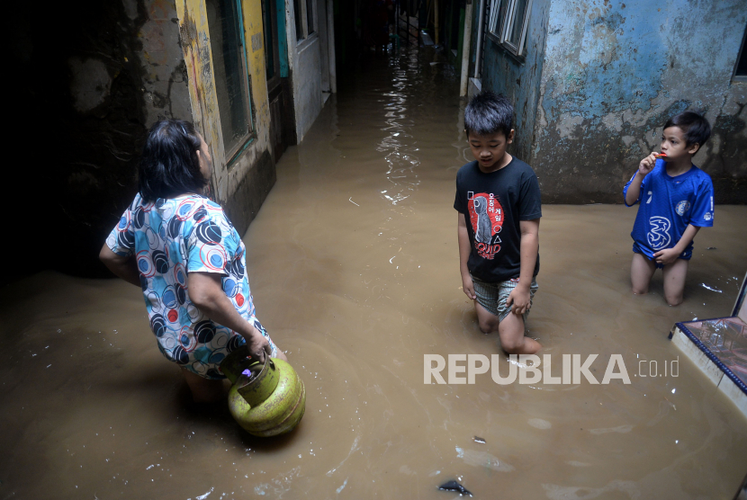 Warga dan anak-anak melintasi banjir yang merendam kawasan Kebon Pala, Kampung Melayu, Jakarta, Sabtu (16/7/2022). Banjir setinggi 40-170 centimeter tersebut terjadi akibat meluapnya air sungai Ciliwung yang dipicu oleh tingginya curah hujan yang mengguyur wilayah Jakarta, Bogor, dan Depok sejak Jumat (15/7/2022) malam hingga Sabtu pagi.Prayogi/Republika.