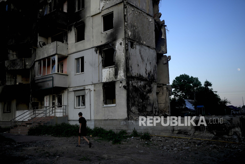 Seorang pria berjalan di depan sebuah bangunan yang dihancurkan oleh serangan di Borodyanka, di pinggiran Kyiv, Ukraina, Ahad, 12 Juni 2022.