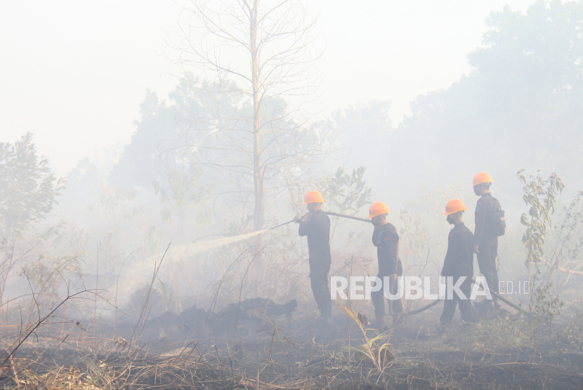 Personel Sat Brimob Polda Kalbar menyemprotkan air ke lahan gambut yang terbakar di Parit Haji Muhsin di Desa Sungai Raya Dalam, Kabupaten Kubu Raya, Kalimantan Barat, Jumat (26/7/2024). 