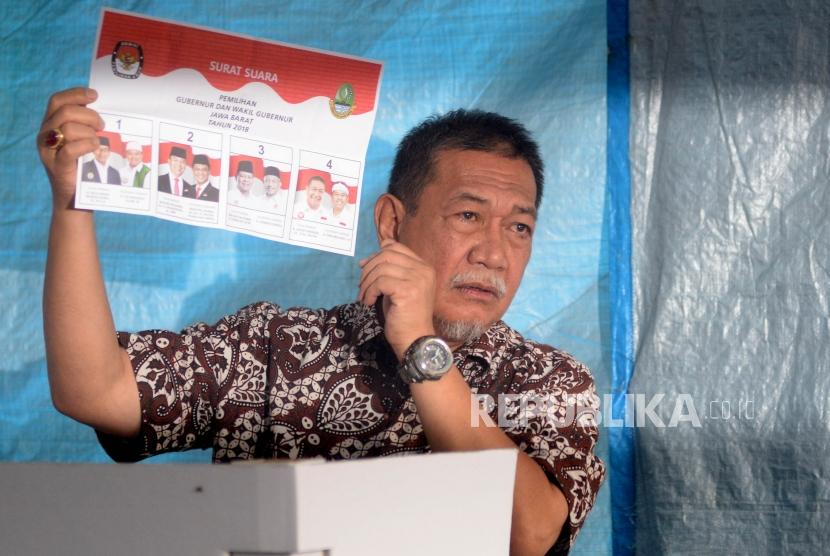 Calon Gubernur Jawa Barat Deddy Mizwar  menunjukan surat suara sebelum melakukan pencoblosan di TPS 61, Jatiwaringin, Bekasi, Jawa Barat, Rabu (27/6).