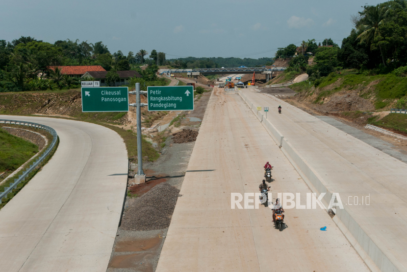 Warga melintas di proyek pembangunan jalan tol Serang-Panimbang di Kecamatan Cikeusal, Kabupaten Serang, Banten, Senin (11/5).