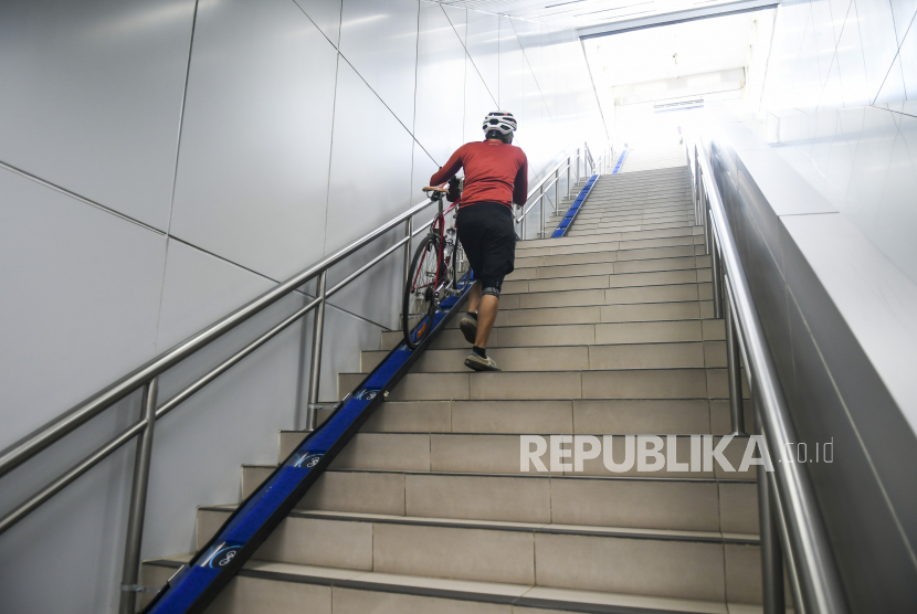 Penumpang membawa sepeda non-lipat di Stasiun MRT Bunderan HI, Jakarta, Ahad (28/3/2021). Pegangan tangan di tangga biasanya terbuat dari baja tahan karat.