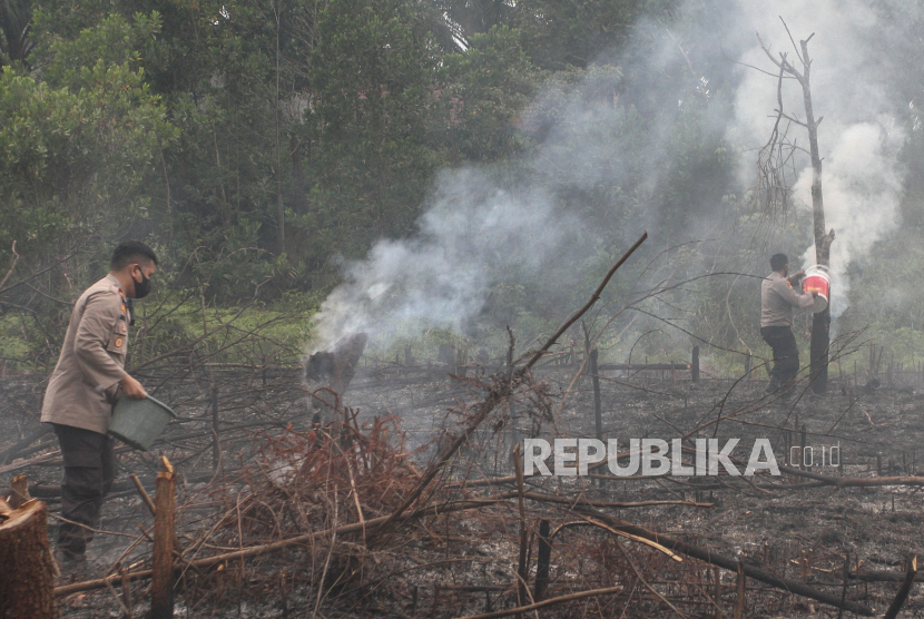 Petugas Kepolisian berusaha memadamkan lahan yang terbakar dengan alat seadanya ketika menunggu bantuan pemadaman dari BPBD Kota Pekanbaru ketika terjadi kebakaran lahan di Pekanbaru, Riau, Rabu (8/7/2020). Polisi dibantu TNI dan BPBD Kota Pekanbaru berhasil memadamkan kebakaran lahan tersebut dan mengamankan dua orang yang diduga menjadi pelaku pembakar lahan. ANTARA FOTO/Rony Muharrman/foc.