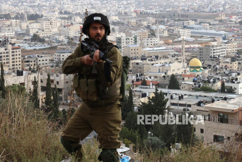 Reaksi seorang tentara Israel yang berpatroli saat melihat jurnalis yang berada di sebuah bukit meliput operasi tentara Isareli di kamp pengungsi Balta, dekat Nablus, Tepi Barat, (19/11/2024). 