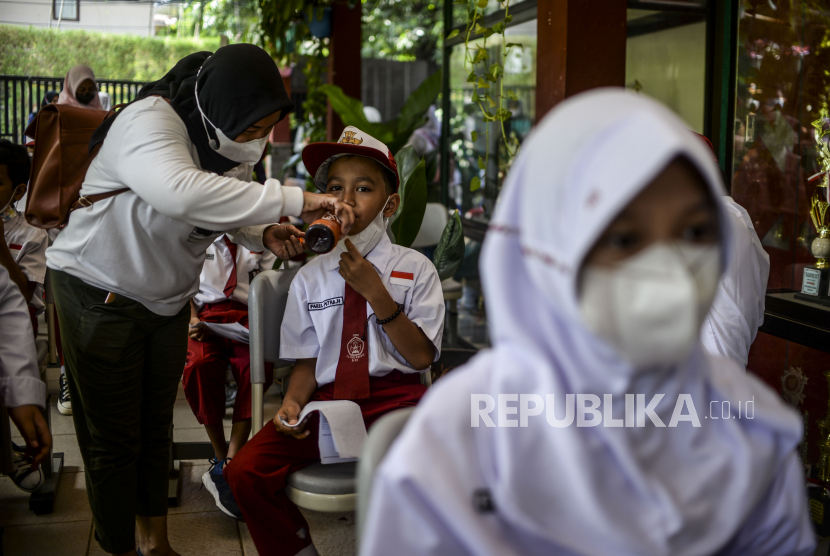 Seorang anak diberikan minum oleh orang tuanya saat menunggu antrean vaksinasi Covid-19 di SDN Cilandak Barat 04, Jakarta, Selasa (14/12). Kementerian Kesehatan memulai vaksinasi Covid-19 untuk anak usia enam hingga sebelas tahun dengan jumlah sasaran vaksinasi mencapai 26,5 juta di Indonesia. Republika/Putra M. Akbar