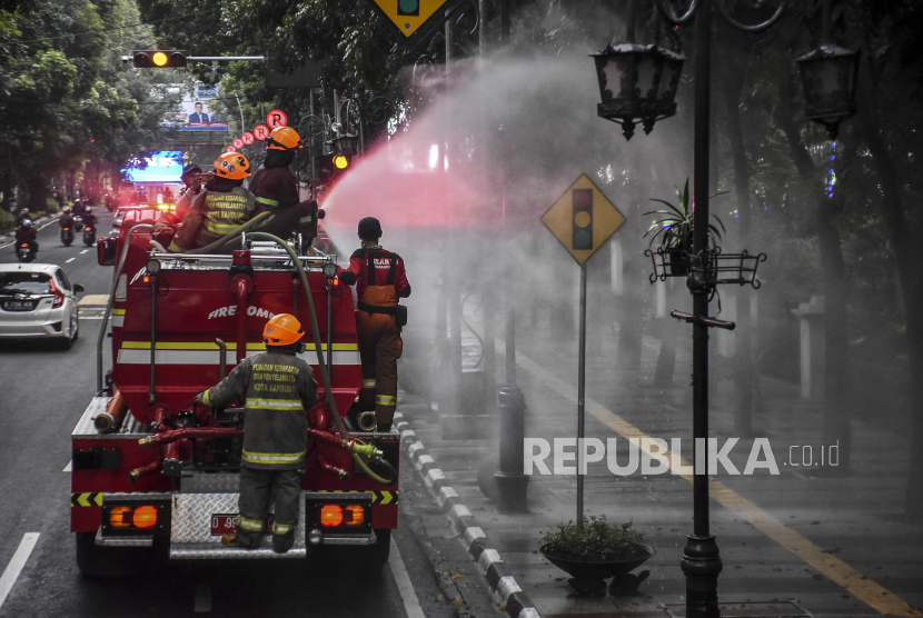 Petugas dari Dinas Pemadam Kebakaran dan Penanggulangan Bencana (Diskar PB) Kota Bandung menyemprotkan cairan disinfektan di ruas Jalan Wastukencana, Kota Bandung, Senin (23/3). 