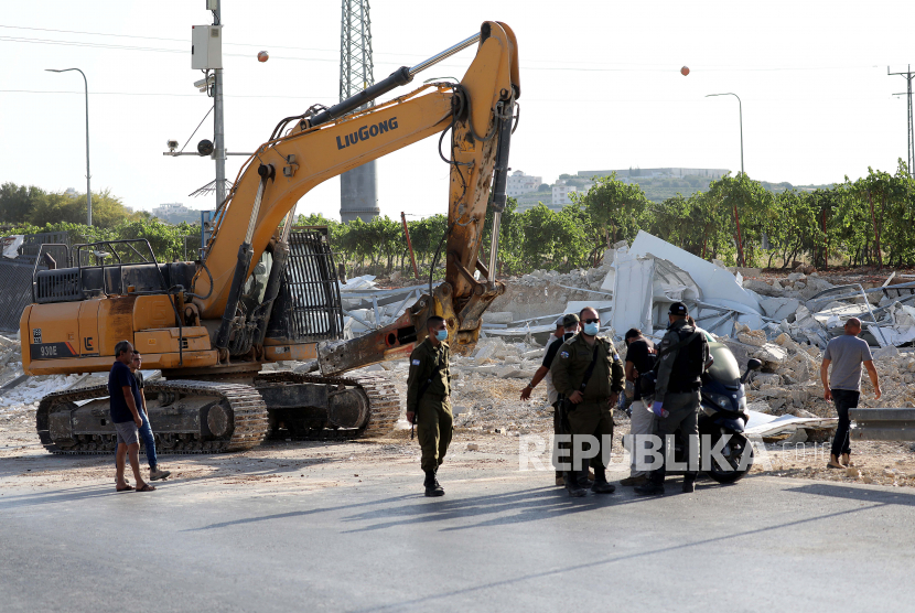 Polisi perbatasan Israel berjaga ketika buldoser Israel menghancurkan gedung-gedung Palestina di kota Hebron Tepi Barat, 21 Juli 2020. Tentara Israel menghancurkan rumah-rumah warga Palestina tanpa izin yang diperlukan untuk membangun unit perumahan atau infrastruktur di Area C Tepi Barat. 