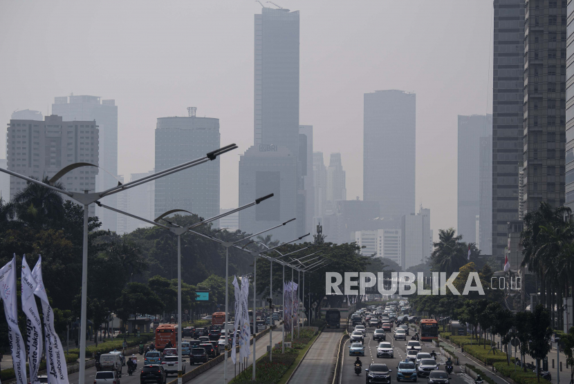 Kendaraan melintas dengan latar belakang gedung bertingkat yang terlihat berkabut di Jalan Jenderal Sudirman, Jakarta. Dinas Lingkungan Hidup DKI memprioritaskan strategi mengatasi pencemaran udara.