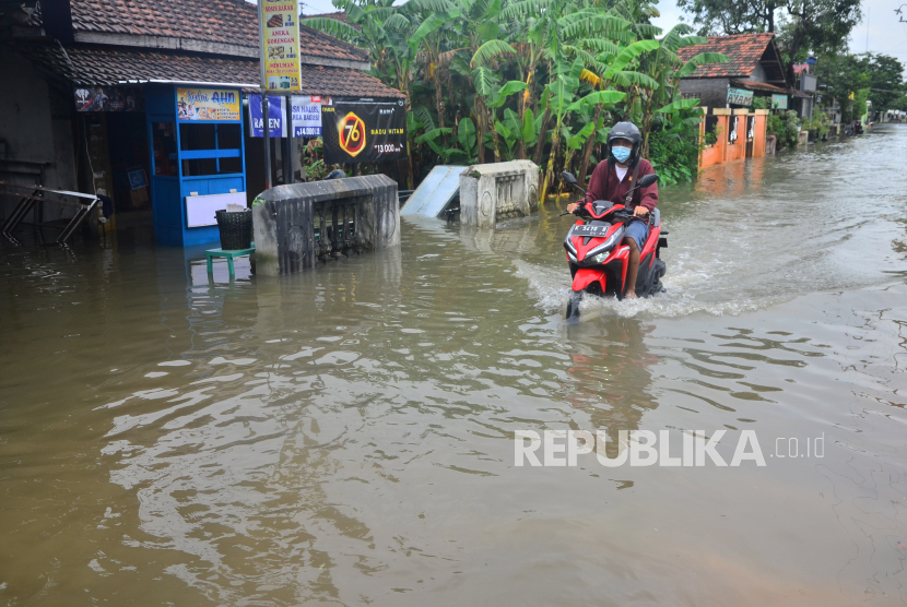 Pengendara sepeda motor melintas di jalan yang tergenang air di Desa Tanjungkarang, Kecamatan Jati, Kabupaten Kudus, Jawa Tengah, Senin (28/2/2022). 