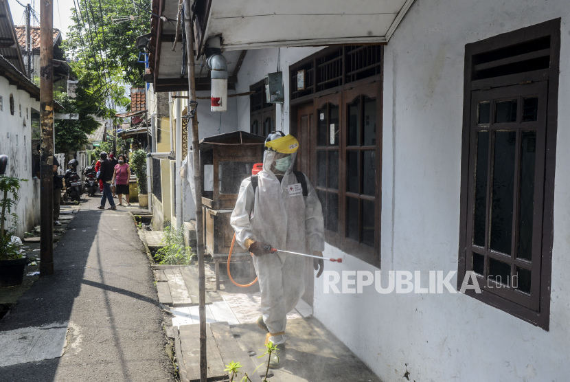 Petugas Palang Merah Indonesia (PMI) menyemprotkan cairan disinfektan di pemukiman padat penduduk di kawasan Petamburan, Jakarta, Jumat (17/4). Penyemprotan cairan disinfektan di lingkungan pemukiman padat penduduk yang lokasinya berdekatan dengan asrama Sekolah Tinggi Teknologi (STT) Bethel itu dilakukan setelah 34 mahasiswa terkonfirmasi positif virus Corona (COVID-19)