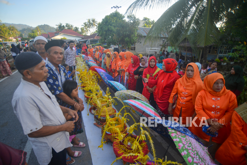 Sejumlah ibu-ibu berdiri di depan dulang yang mereka bawa saat acara tradisi Limau Barongge, di Sungai Pisang, Padang, Sumatera Barat, Jumat (1/4/2022). Limau Barongge merupakan tradisi silaturahmi antar suku di Sungai Pisang menyambut bulan ramadhan, yakni dengan bersama-sama mengarak dulang yang dihias kemudian menyeka wajah dengan air perasan limau sebagai simbol menyucikan diri. 