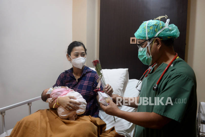 Dokter memberikan bunga dan kue kepada pasien yang baru melahirkan.