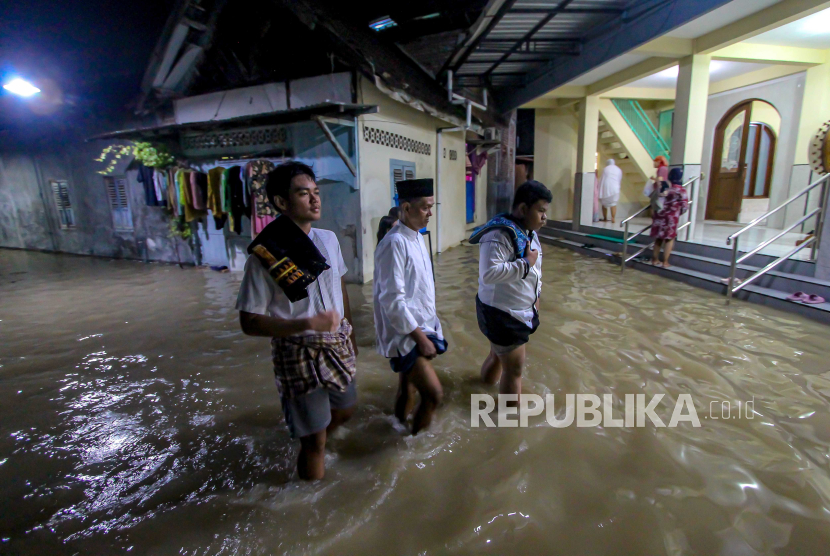 Umat Islam berjalan melintasi genangan air banjir akibat luapan Sungai Bengawan Solo. BPBD Probolinggo sebut lebih dari 3.000 kepala keluarga yang terdampak banjir.