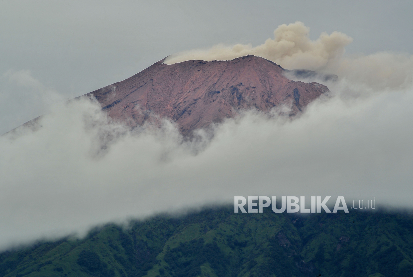 Gunung Kerinci mengembuskan gas dan material ke udara yang terlihat dari Gunung Tujuh, Kerinci, Jambi.