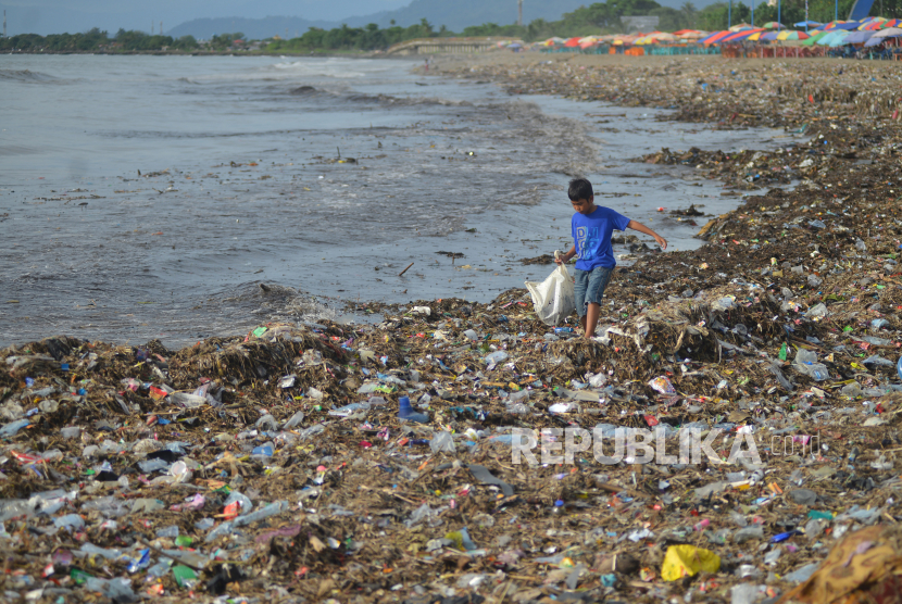 Anak-anak memilih barang yang masih bisa dimanfaatkan di antara tumpukan sampah di objek wisata Pantai Padang, Sumatera Barat.