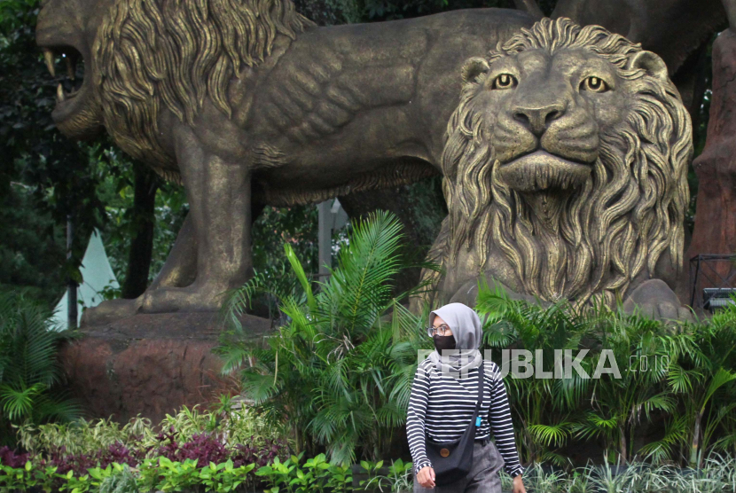 Pejalan kaki melintas di depan patung Tiga Singa. Ilustrasi
