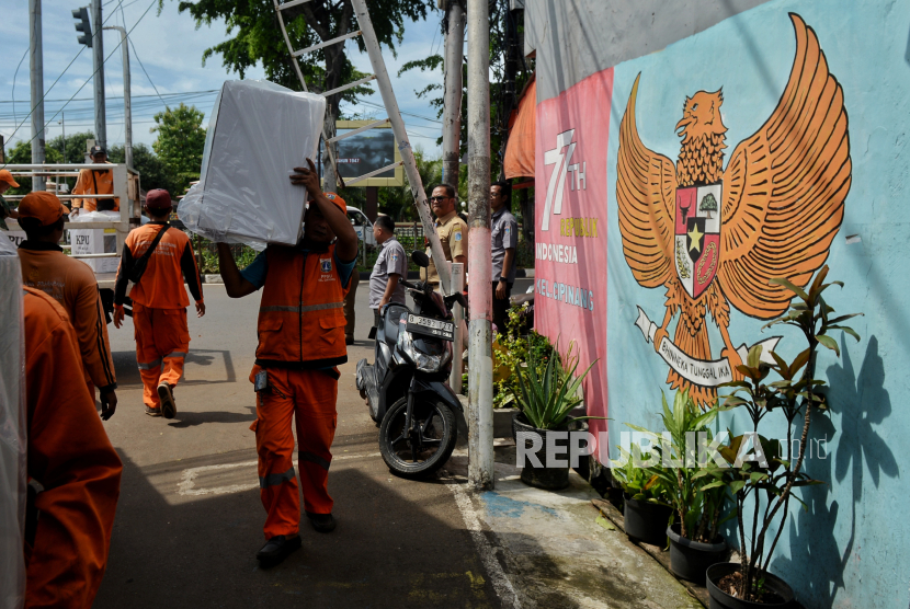 Petugas PPSU membantu petugas KPPS mendistribusikan kotak suara ke tempat pemungutan suara (TPS) di kawasan Cipinang, Jakarta Timur, Selasa (13/2/2024). 