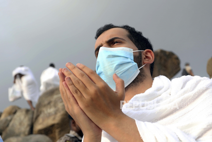  Amerika Puji Saudi Usai Penyelenggaraan Haji 2020. Foto: Seorang jamaah haji berdoa di atas bukit berbatu yang dikenal sebagai Gunung Belaskasih di Dataran Arafat, saat ia mengenakan topeng untuk melindungi dirinya dari virus corona selama ziarah haji tahunan di dekat kota suci Mekah, Arab Saudi, Kamis, 30 Juli , 2020. Haji tahun ini diturunkan secara dramatis dari 2,5 juta jamaah menjadi sedikitnya 1.000 karena pandemi coronavirus.