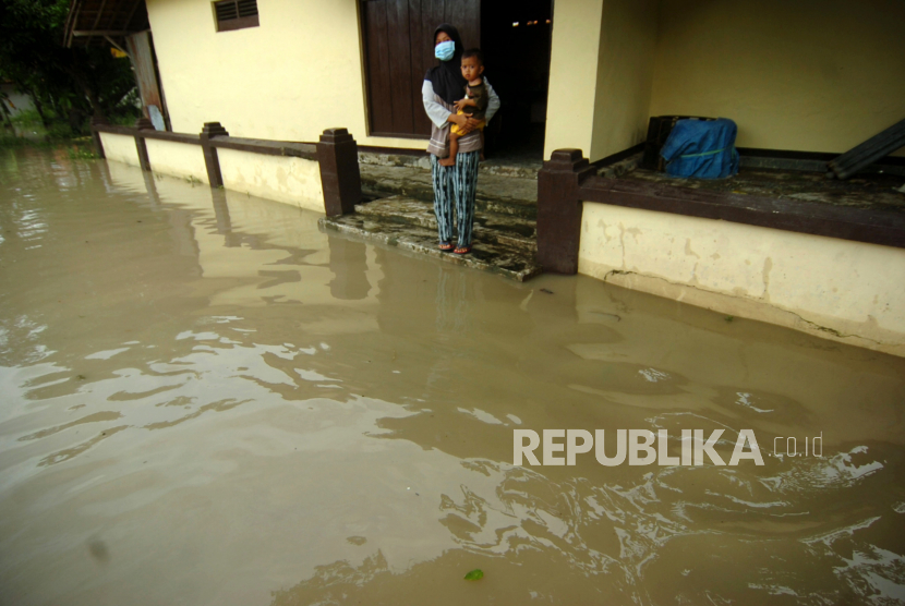 Warga berada di depan rumahnya yang terendam banjir di Desa Bojong, Brebes, Jawa Tengah, Rabu (13/1/2021). (Ilustrasi)