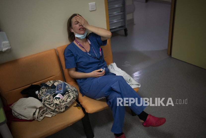FILE - Perawat Marie-Laure Satta membelai wajahnya selama jeda dalam shift Malam Tahun Baru di unit perawatan intensif COVID-19 di rumah sakit la Timone di Marseille, Prancis selatan, 31 Desember 2021. Profesional kesehatan di rumah sakit umum dan pusat perawatan di seluruh Prancis berhenti bekerja pada Selasa (7/6/2022).