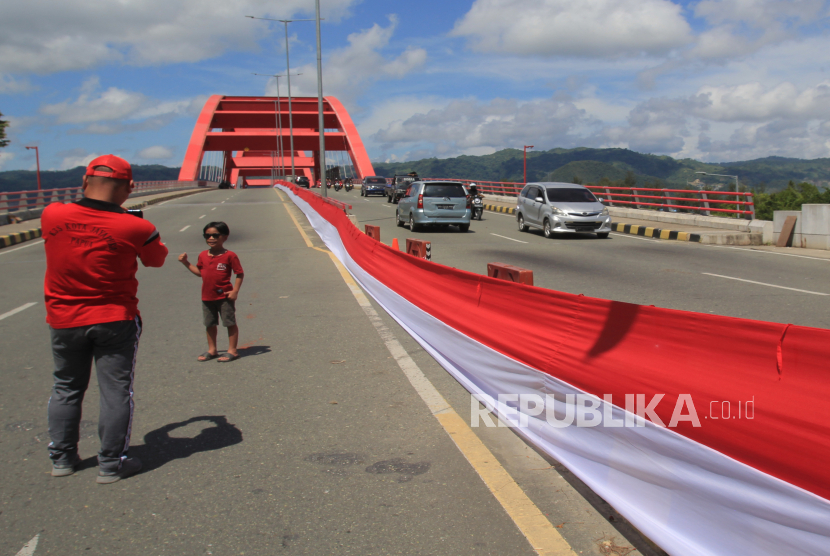 Warga berswafoto di dekat Bendera Merah Putih yang terbentangan di Jembatan Youtefa Holtekamp, Kota Jayapura, Papua, Rabu (1/5/2024).