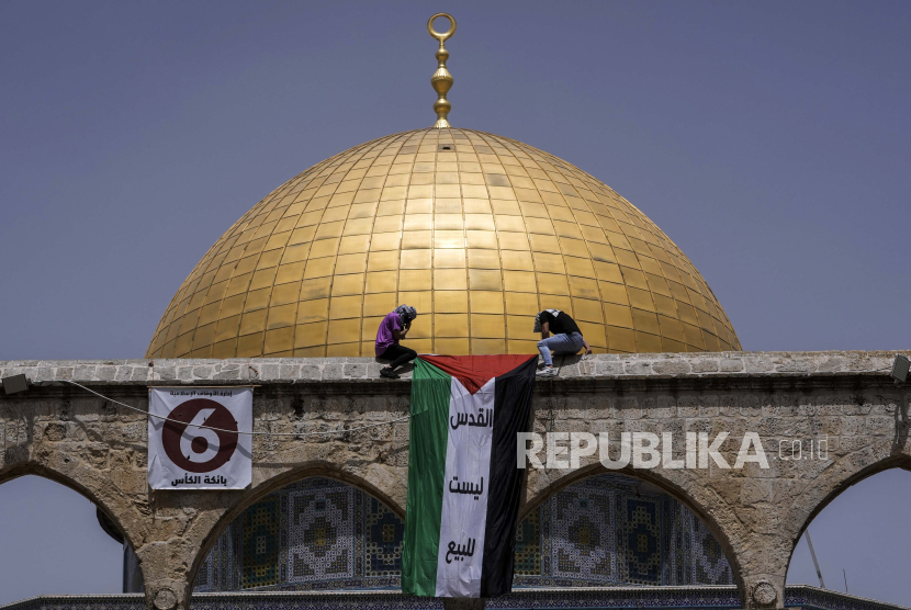 Warga Palestina mengibarkan bendera nasional selama bulan suci Ramadhan di kompleks Masjid Al Aqsa di Yerusalem.