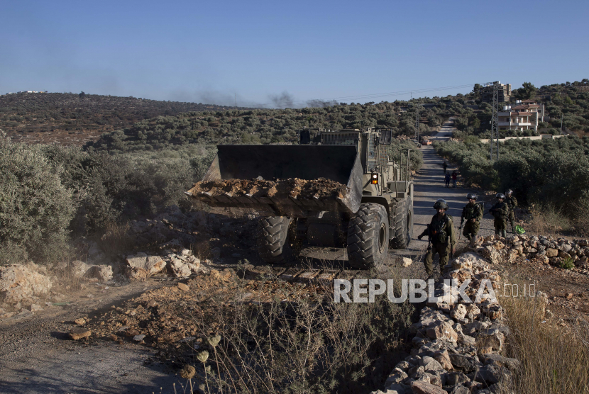 Seorang tentara Israel mengarahkan buldoser yang menutup penghalang di jalan dekat pos terdepan pemukiman Yahudi Eviatar yang dengan cepat didirikan bulan lalu, di desa Palestina Beita, dekat kota Nablus, Tepi Barat, Minggu, 27 Juni 2021.