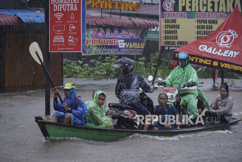 Sejumlah warga melintasi Jalan Lintas Melawi yang terdampak banjir dengan perahu di Ladang, Kabupaten Sintang, Kalimantan Barat, Jumat (12/11/2021). Banjir yang melanda 12 kecamatan tersebut belum juga surut selama tiga pekan terakhir akibat curah hujan yang tinggi, sementara pendistribusian bantuan masih terkendala di sejumlah wilayah karena sulitnya akses menuju lokasi. 