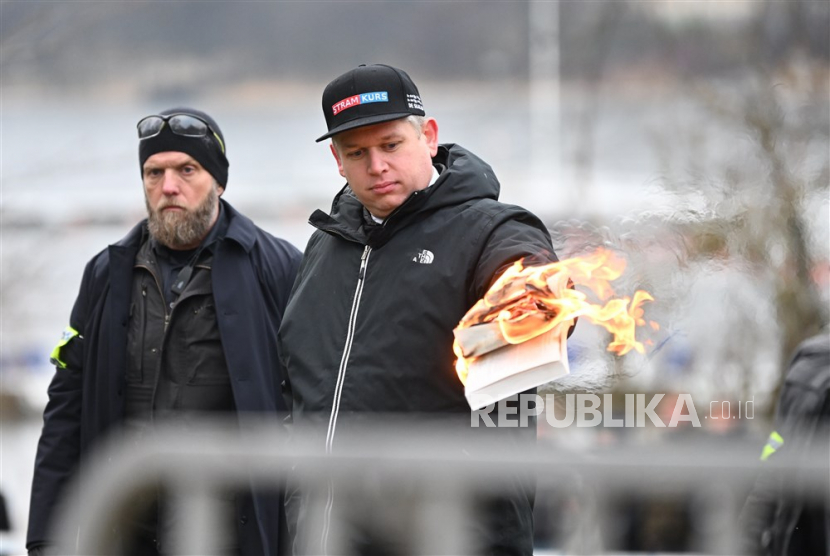 Pemimpin partai politik sayap kanan Denmark Stram Kurs, Rasmus Paludan, membakar salinan Alquran sambil diawasi oleh petugas polisi saat dia melakukan protes di luar kedutaan Turki di Stockholm, Swedia, 21 Januari 2023. Rasmus Paludan Ingin Bakar Alquran Lagi