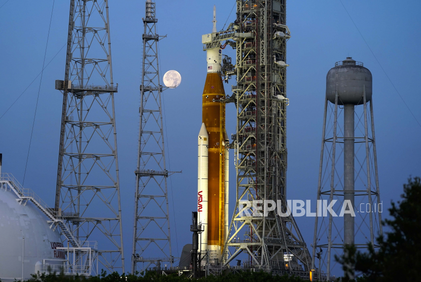  FILE - Bulan terbenam di depan roket NASA Artemis dengan pesawat ruang angkasa Orion di atas landasan 39B di Kennedy Space Center, Rabu, 15 Juni 2022, di Cape Canaveral, Florida. Dengan peluncuran yang direncanakan pada Senin, 29 Agustus 2022 , roket setinggi 322 kaki akan mencoba mengirim kapsul awak kosong ke orbit bulan yang sangat jauh.