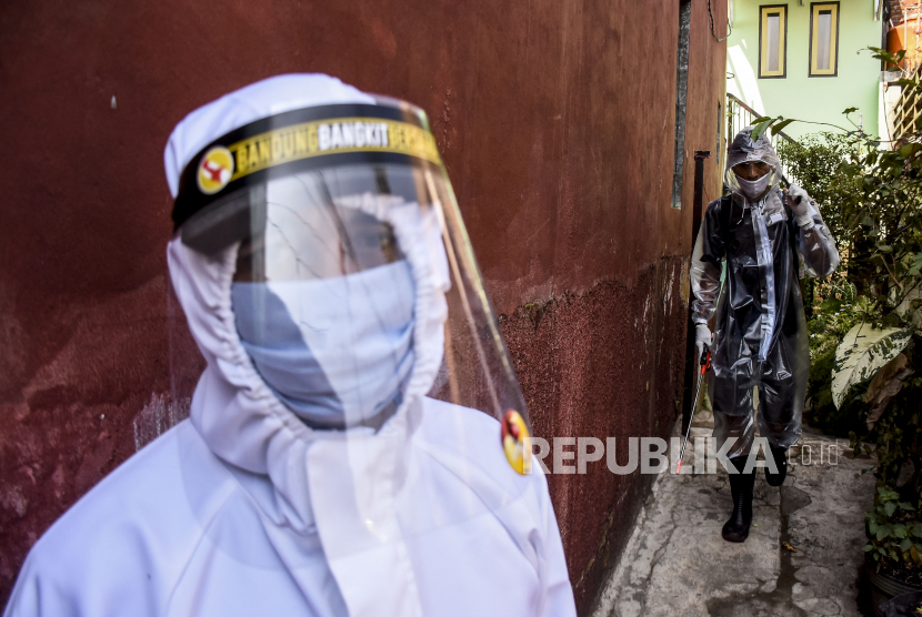 Petugas dari pengurus RW 11 menggunakan alat pelindung diri (APD) menyemprotkan cairan disinfektan di sekitar pemukiman warga di Cibeunying Kidul, Kota Bandung, Ahad (13/9). Penyemprotan disinfektan mandiri dari swadaya warga setempat dilakukan untuk meminimalisir penyebaran Covid-19 di kawasan tersebut. Foto: Abdan Syakura/Republika
