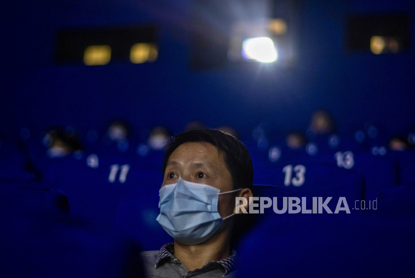 Orang-orang memakai topeng pelindung wajah dan mengamati jarak sosial ketika menonton film di sebuah bioskop di Shanghai, Cina, 20 Juli 2020. Ilustrasi