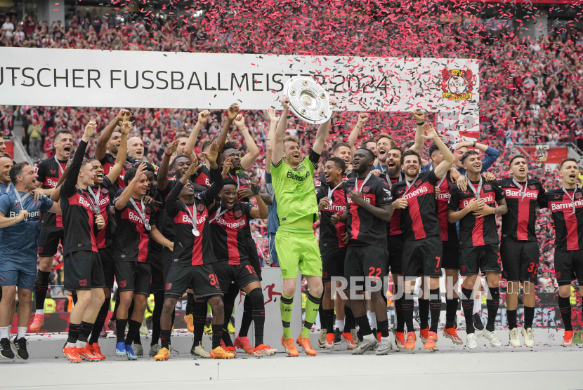 Para pemain Leverkusen merayakan dengan trofi saat memenangkan pertandingan sepak bola Bundesliga Jerman antara Bayer Leverkusen dan FC Augsburg di BayArena di Leverkusen, Jerman, Sabtu, (18/5/2024).
