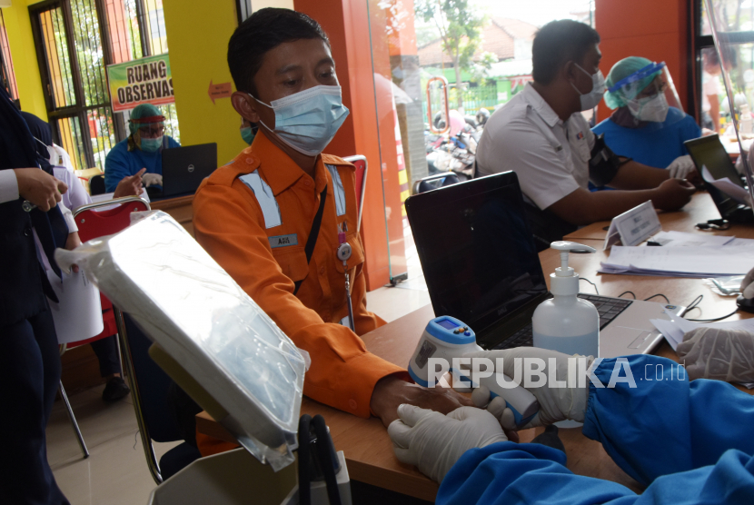 Petugas medis memeriksa suhu tubuh karyawan PT Kereta Api Indonesia (KAI) Daerah Operasi (Daop) 7 Madiun sebelum menerima suntikan vaksin COVID-19 di Puskesmas Oro oro Ombo Kota Madiun, Jawa Timur, Kamis (4/3/2021). Vaksinasi massal karyawan dan karyawati PT KAI tersebut dilakukan di dua tempat yaitu Puskesmas Oro oro Ombo dan Tawangrejo untuk mencegah kerumunan. ANTARA FOTO/Siswowidodo/rwa.