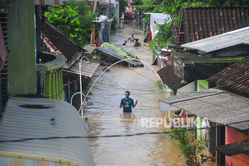 Warga melintasi jalan yang tergenang di Desa Gubug, Gubug, Grobogan, Jawa Tengah, Selasa (6/2/2024). Banjir akibat hujan deras serta jebolnya beberapa tanggul sungai Tuntang itu menyebabkan jalan penghubung Purwodadi-Semarang itu lumpuh dan arus lalu-lintas dialihkan serta ribuan rumah terendam di 11 Kecamatan. 