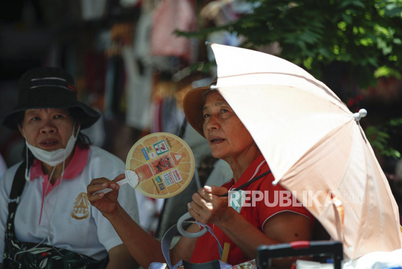  Seorang pejalan kaki menggunakan kipas angin untuk mendinginkan dan melindungi diri dari sinar matahari. Pemerintah Kota Padang mengajak masyarakat setempat untuk mengurangi aktivitas di luar ruangan karena cuaca panas. 