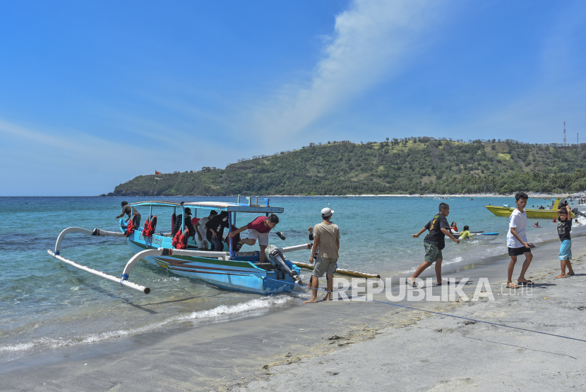 Sejumlah pengunjung turun dari perahu usai berkeliling di Pantai Wisata Nipah, Kecamatan Pemenang, Lombok Utara, NTB. Indonesia menjadi satu dari lima negara yang berhasil menurunkan kasus secara signifikan.