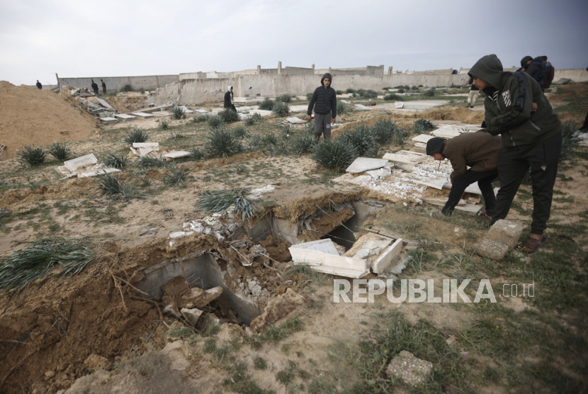 Warga Palestina memeriksa kuburan yang rusak menyusul serangan tank Israel di kuburan di kamp pengungsi Khan Younis, Jalur Gaza selatan, Rabu, (17/1/2024).