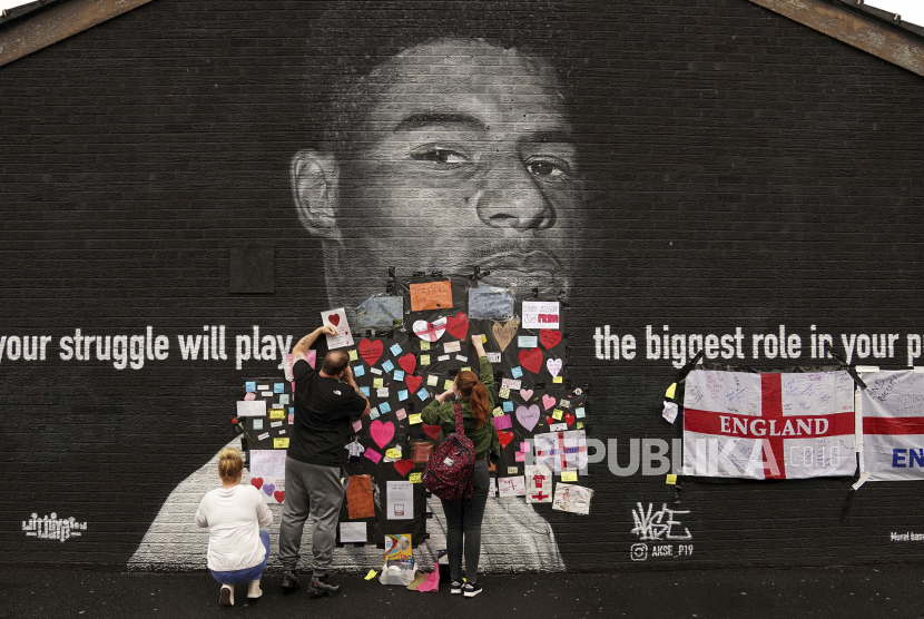 People place messages of support on top of bin liners that were taped over offensive wording on the mural of Manchester United striker and England player Marcus Rashford on the wall of the Coffee House Cafe on Copson Street, which appeared vandalised the morning after the England soccer team lost the Euro 2021 final against Italy, in Withington, Manchester, England, Monday,  July 12, 2021.  British Prime Minister Boris Johnson has condemned the racist abuse directed at three Black England players who missed their penalties in the team’s shootout loss to Italy in the final of the European Championship on Sunday. Johnson tweeted that “those responsible for this appalling abuse should be ashamed of themselves.” Marcus Rashford’s penalty hit the post and spots kicks from Bukayo Saka and Jadon Sancho were saved by Italys goalkeeper. 
