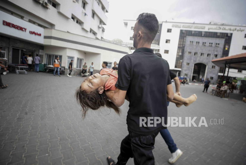 A Palestinian man carries a wounded person in Al-Shifa hospital in Gaza City.