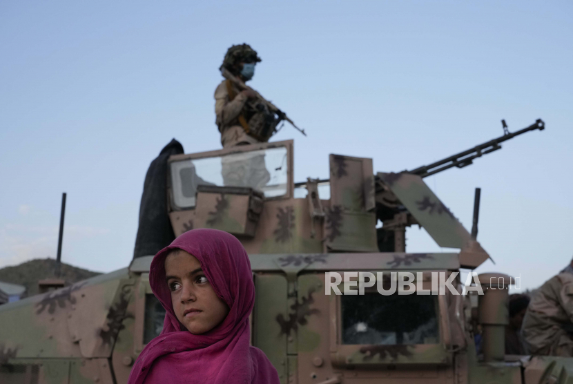  Gadis Afghanistan berdiri di samping seorang pejuang Taliban setelah gempa bumi di distrik Gayan di provinsi Paktika, Afghanistan, Sabtu, 25 Juni 2022. acebook telah menghapus akun setidaknya dua outlet media milik pemerintah Taliban.